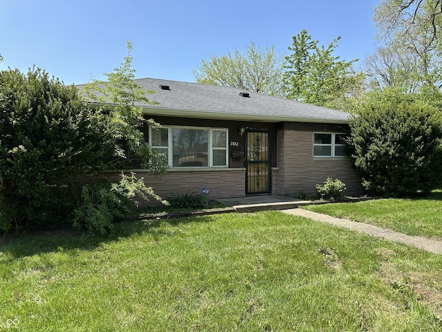 view of front of home with roof with shingles, stone siding, and a front yard
