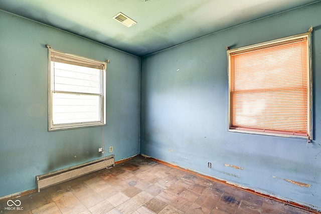 spare room featuring visible vents and a baseboard heating unit