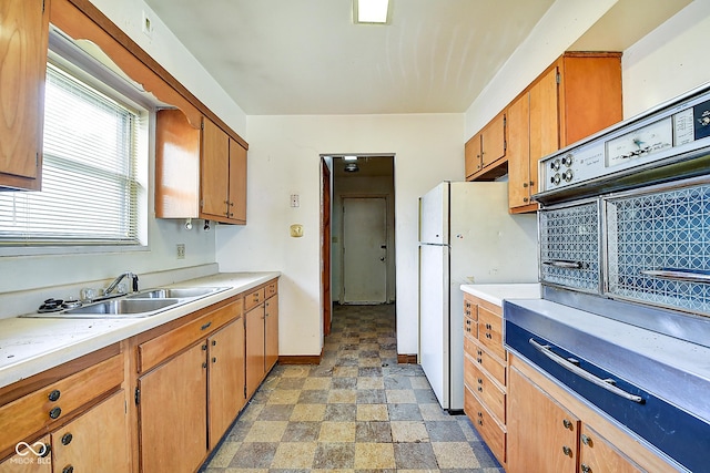 kitchen featuring freestanding refrigerator, stone finish floor, a sink, and light countertops
