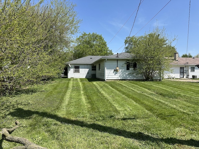 rear view of house featuring a yard and central AC