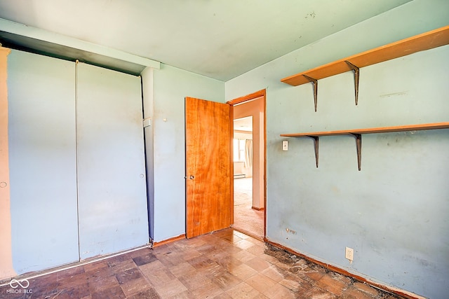 unfurnished bedroom with a closet and a baseboard radiator