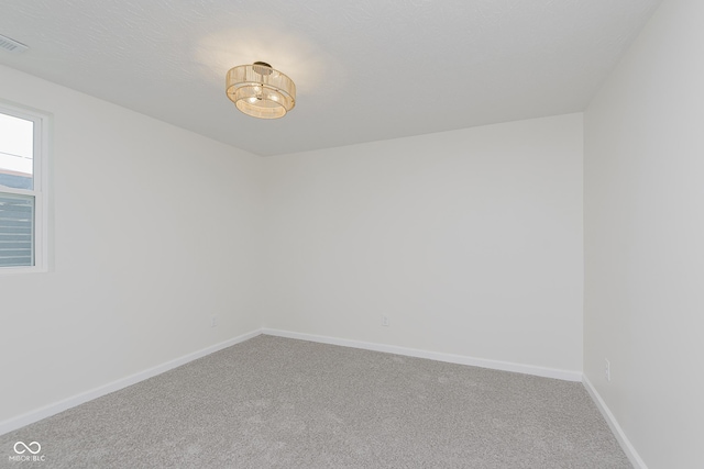 carpeted empty room with baseboards and a chandelier