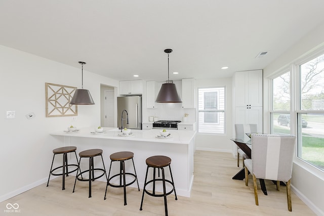 kitchen with a peninsula, high end fridge, stove, and a kitchen bar