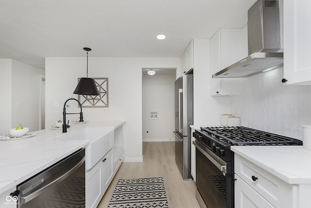 kitchen with freestanding refrigerator, black range with gas stovetop, wall chimney exhaust hood, light wood-style flooring, and dishwasher