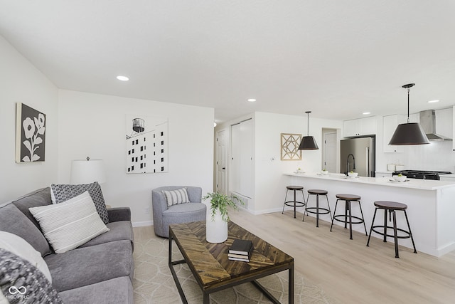 living room featuring recessed lighting, baseboards, and light wood-type flooring