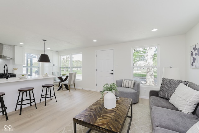 living room with recessed lighting, baseboards, light wood-type flooring, and a wealth of natural light