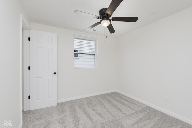 carpeted spare room with a ceiling fan and baseboards
