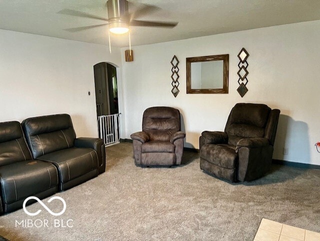 carpeted living area with arched walkways and a ceiling fan