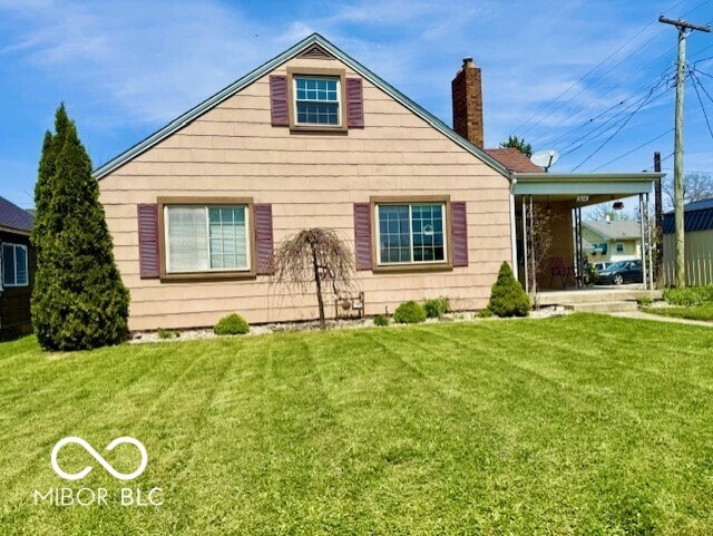 rear view of house featuring a lawn and a chimney