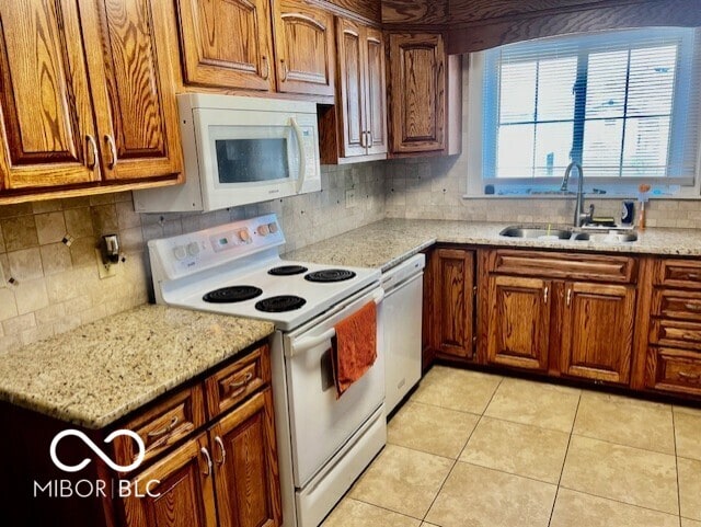 kitchen featuring white appliances, brown cabinets, tasteful backsplash, a sink, and light tile patterned floors