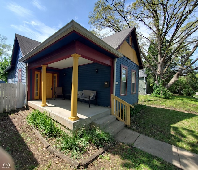 1050 Jefferson Ave, Indianapolis, IN 46201 - exterior space featuring a porch, a shingled roof, a lawn, and fence