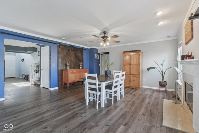 2116 Crimson Ln, Lebanon, IN 46052 - dining space with a barn door, a ceiling fan, dark wood-type flooring, a fireplace, and crown molding