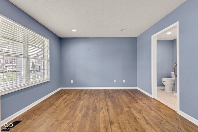 spare room with baseboards, recessed lighting, a textured ceiling, and wood finished floors