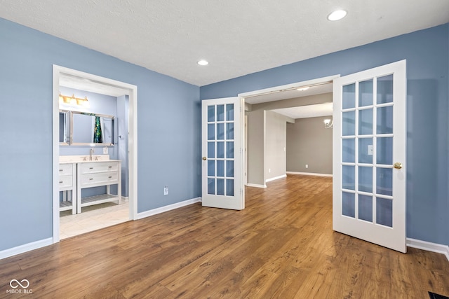 interior space with baseboards, french doors, a sink, and wood finished floors