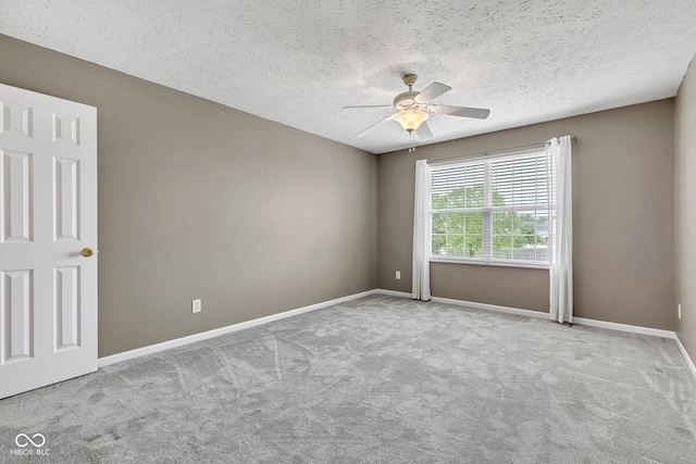 carpeted empty room with ceiling fan, a textured ceiling, and baseboards