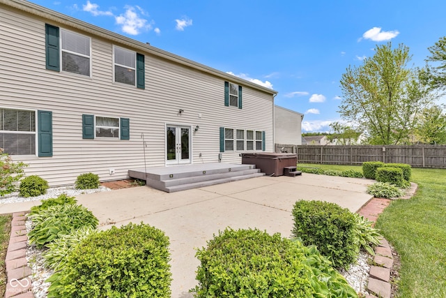rear view of house featuring a hot tub, a patio area, french doors, and fence