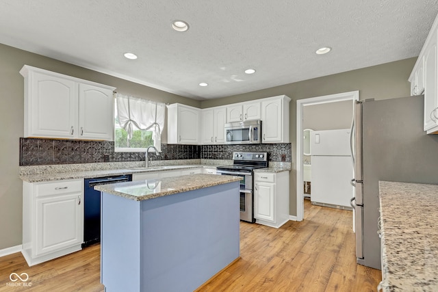 kitchen with light wood finished floors, decorative backsplash, stainless steel appliances, and a sink
