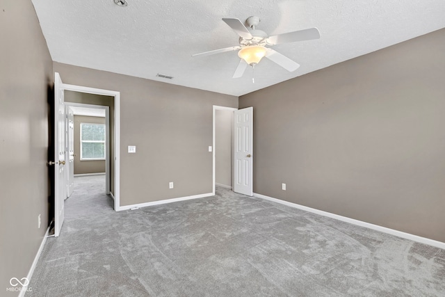unfurnished bedroom with a textured ceiling, carpet floors, baseboards, and visible vents