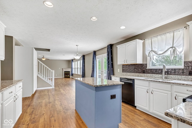 kitchen with black dishwasher, a kitchen island, a sink, and a textured ceiling