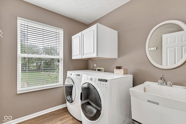 laundry area featuring cabinet space, washer and clothes dryer, plenty of natural light, and light wood finished floors