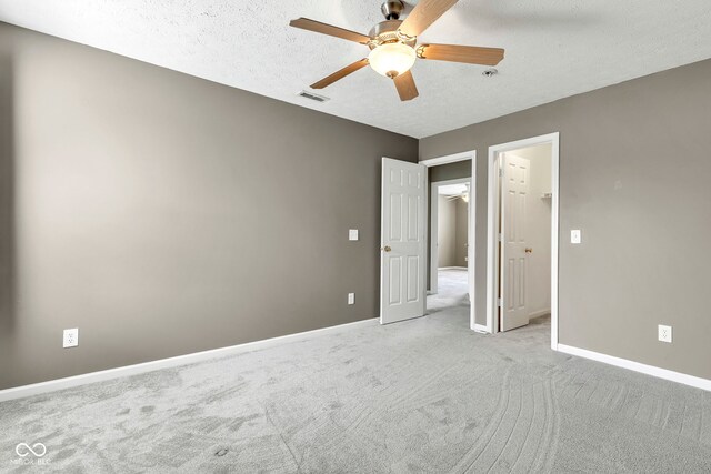 unfurnished bedroom with a textured ceiling, baseboards, carpet flooring, visible vents, and a spacious closet