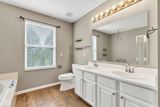 bathroom with toilet, visible vents, a sink, and wood finished floors
