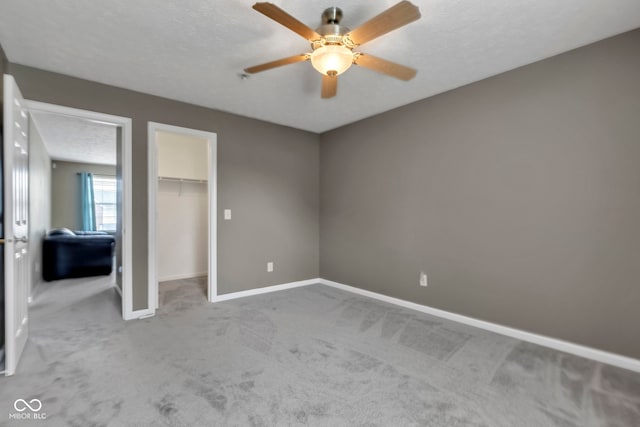unfurnished bedroom with a closet, a textured ceiling, baseboards, carpet flooring, and ceiling fan