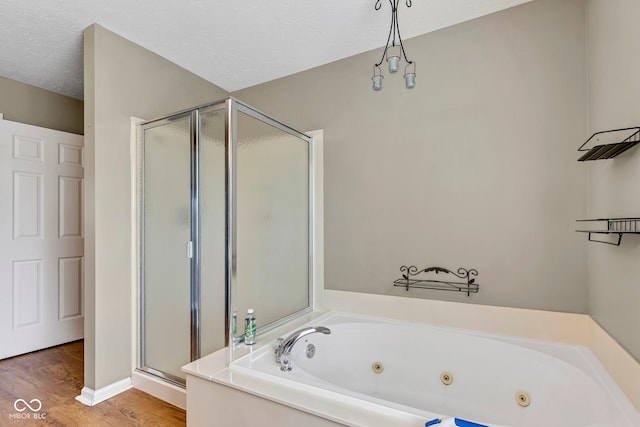 bathroom with a stall shower, wood finished floors, a textured ceiling, and a whirlpool tub