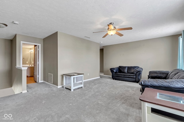 carpeted living room featuring a textured ceiling, visible vents, baseboards, and a ceiling fan