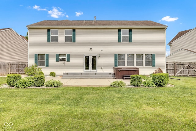 back of house featuring a lawn, french doors, a hot tub, a patio area, and a fenced backyard