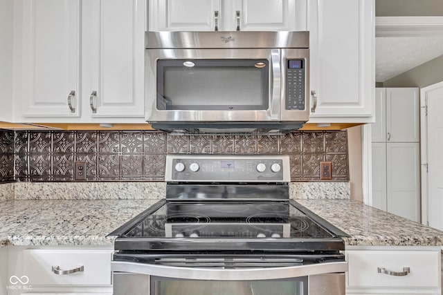 kitchen featuring stainless steel appliances, white cabinets, and decorative backsplash