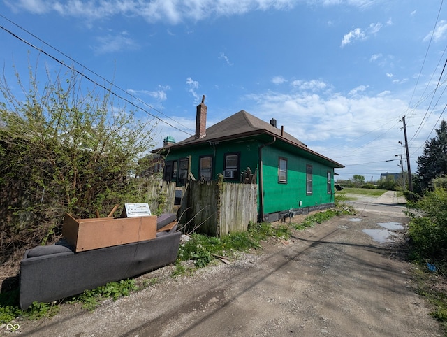 view of side of property with fence and a chimney
