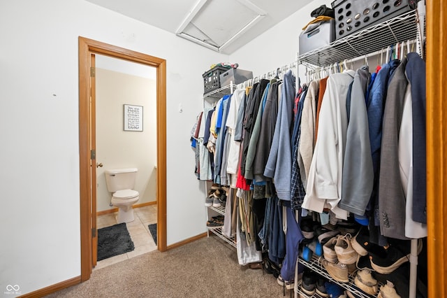 walk in closet featuring carpet floors, tile patterned floors, and attic access