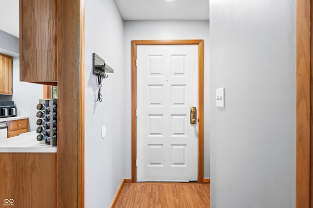 doorway to outside featuring baseboards and light wood-type flooring