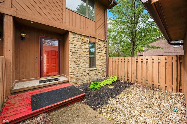 entrance to property with fence and stone siding