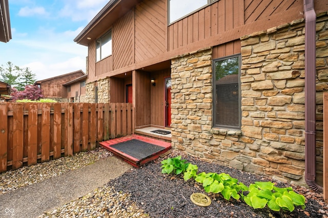 property entrance with fence and stone siding
