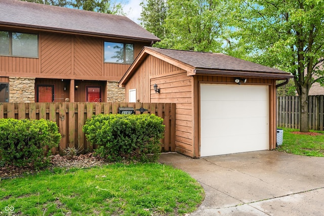 garage with concrete driveway and fence
