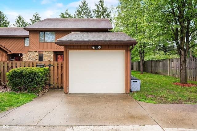 garage featuring fence and concrete driveway