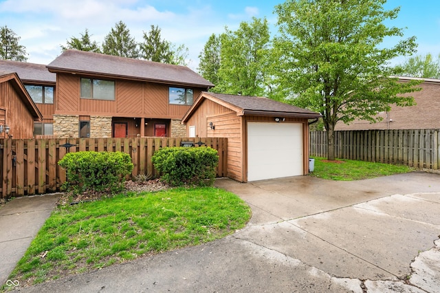 view of front of property with an attached garage, driveway, a fenced front yard, and stone siding