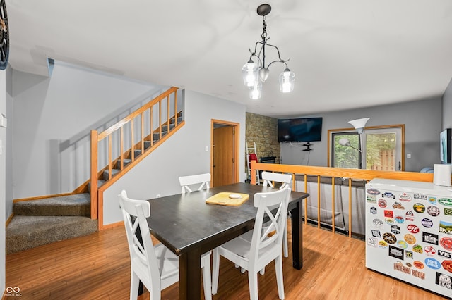 dining room with stairs, wood finished floors, and a chandelier