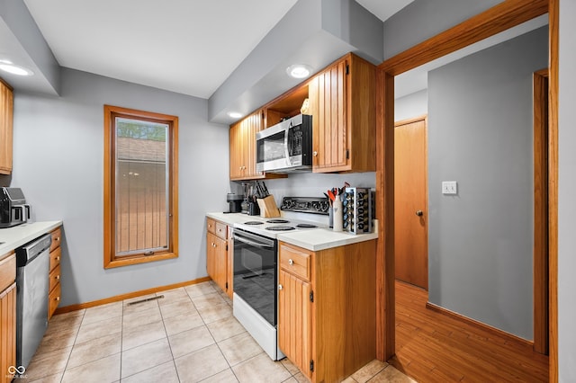 kitchen with visible vents, appliances with stainless steel finishes, brown cabinets, light countertops, and baseboards