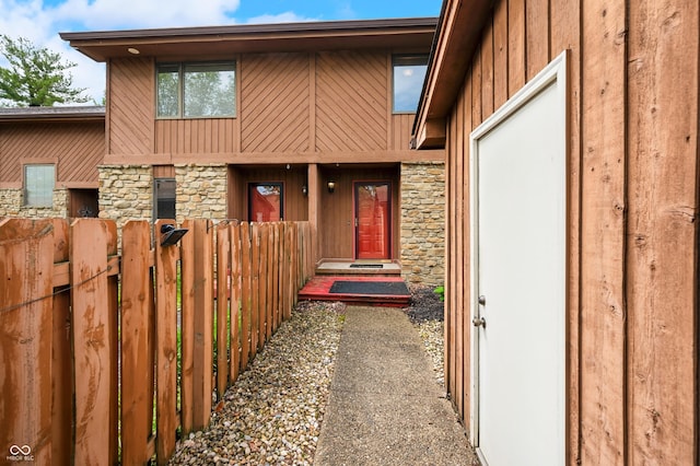 view of front facade featuring board and batten siding, fence, and stone siding