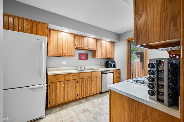 kitchen featuring a sink, light countertops, freestanding refrigerator, light tile patterned floors, and stainless steel dishwasher