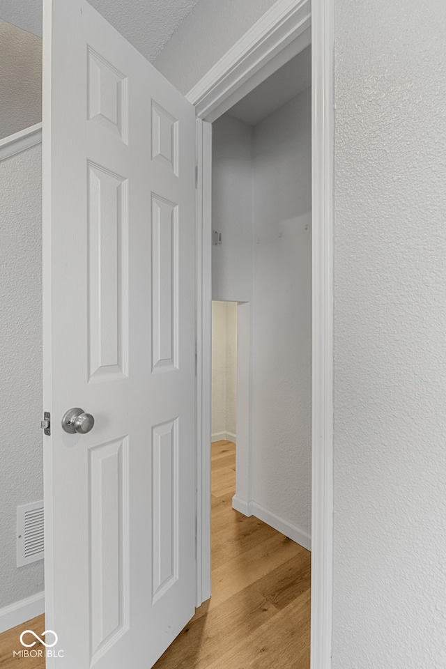 corridor with visible vents, baseboards, and wood finished floors