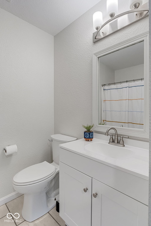 bathroom with vanity, a textured wall, toilet, a textured ceiling, and tile patterned floors