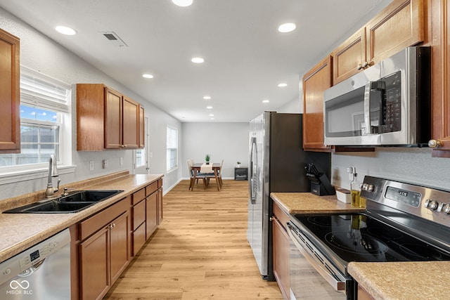 kitchen featuring brown cabinetry, light wood-style floors, recessed lighting, a sink, and appliances with stainless steel finishes