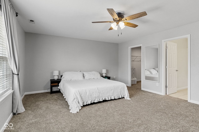 bedroom with light colored carpet, baseboards, ceiling fan, and a spacious closet