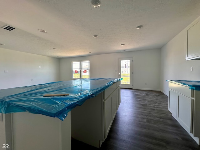 1216 Mcbride St, Greenfield, IN 46140 - kitchen with dark wood-style floors, white cabinetry, a center island, a textured ceiling, and dark countertops