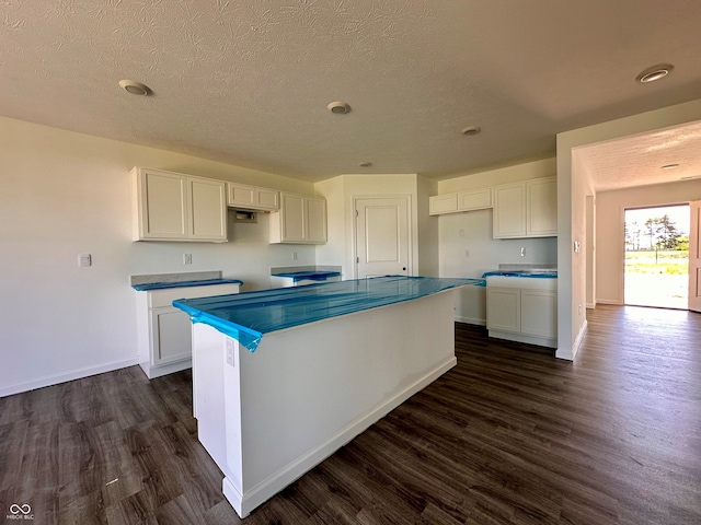 1216 Mcbride St, Greenfield, IN 46140 - kitchen with dark wood-type flooring, white cabinets, a kitchen island, and a textured ceiling