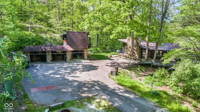 1686 Borders Rd, Nashville, IN 47448 - view of front facade with driveway, a wooded view, a carport, and stone siding